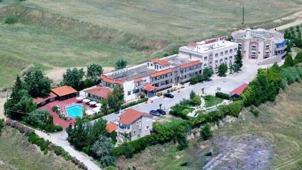 Vista aerea di un complesso alberghiero con diversi edifici, una piscina e una zona verde curata.