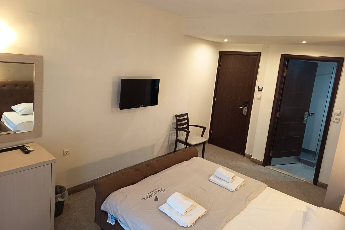 Une chambre d’hôtel avec un lit, une chaise, une télévision et une porte.