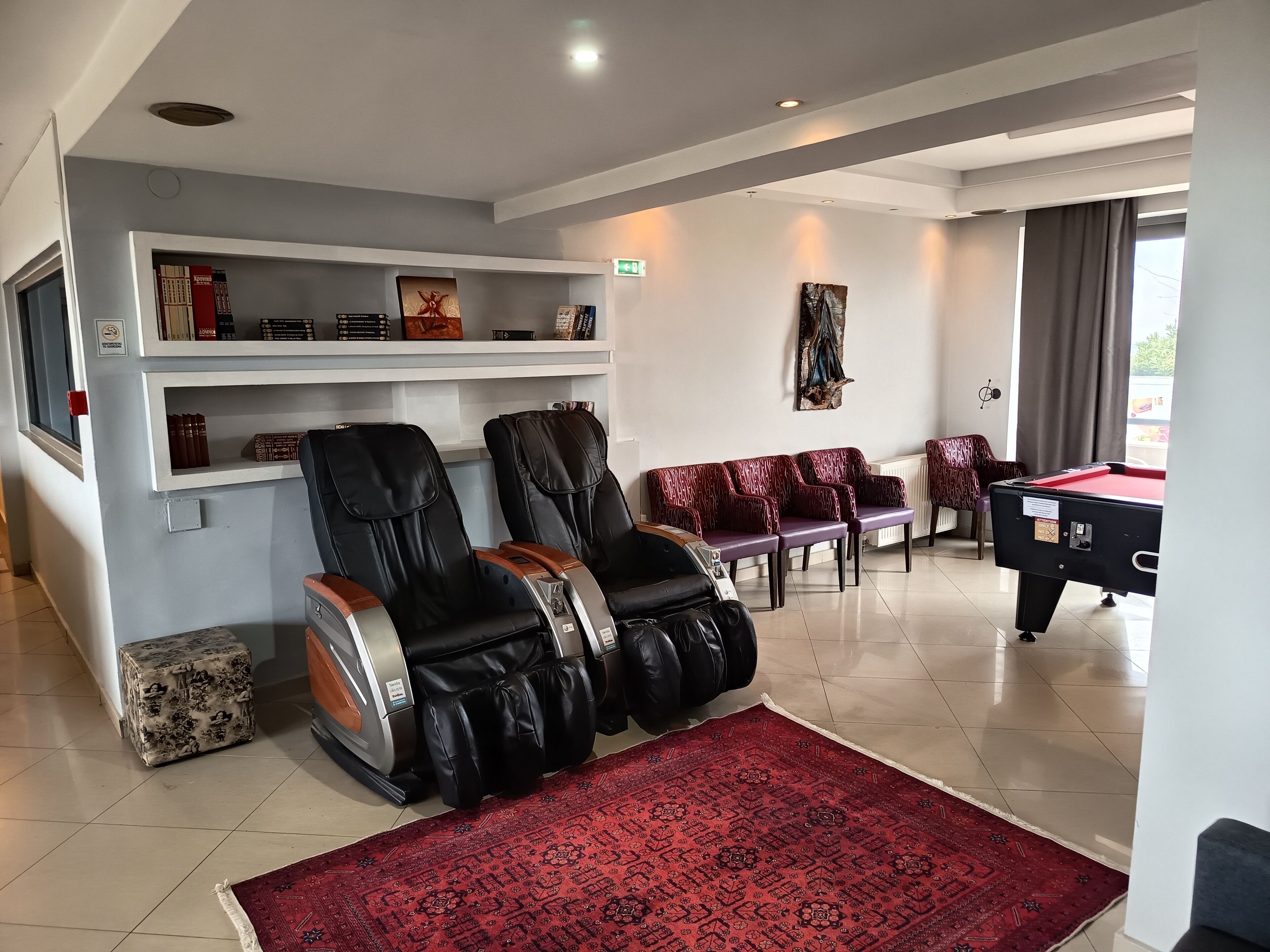 Una habitación con sillones de masaje, una mesa de billar y un tapete rojo con estampado.