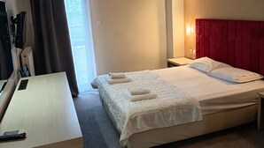Una camera d'albergo con un letto, una scrivania, una televisione e un condizionatore.