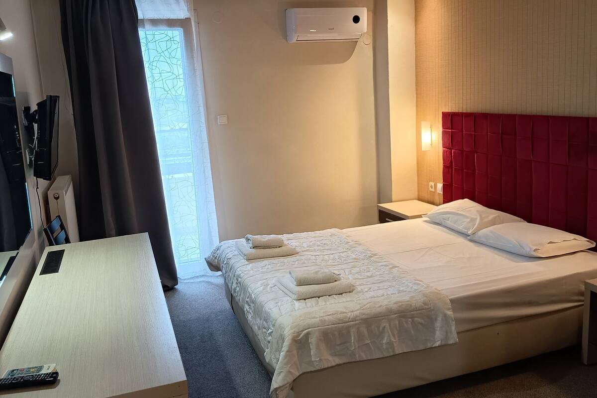 Une chambre d’hôtel équipée d’un lit, d’un bureau, d’une télévision et d’un appareil de climatisation.