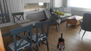 Un salon avec un canapé, des fauteuils, une table basse et un chien.