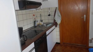 Une cuisine de taille réduite avec des meubles blancs, une cuisinière, un four et un évier.