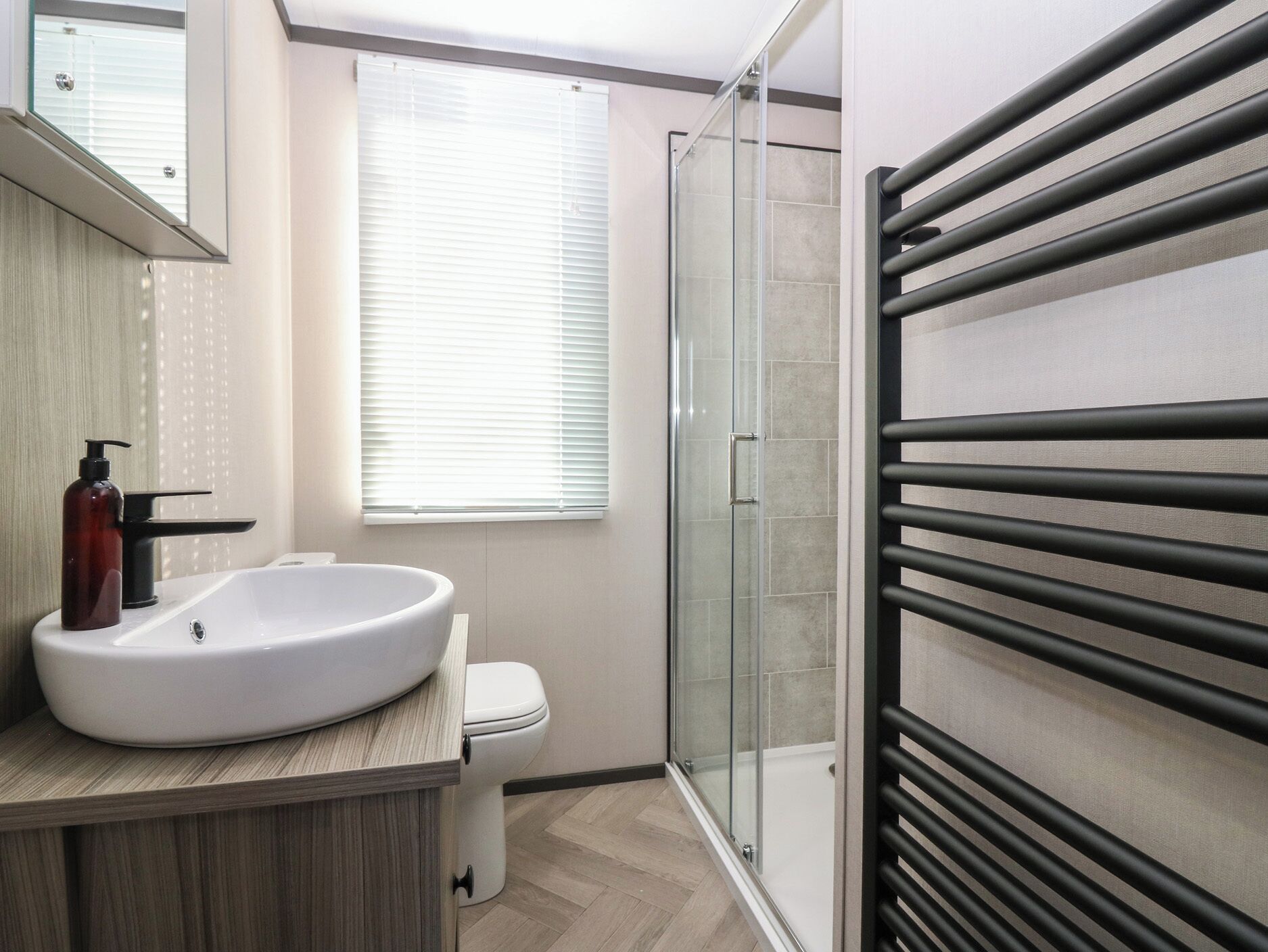 A modern bathroom with a large sink, toilet, and glass shower enclosure.