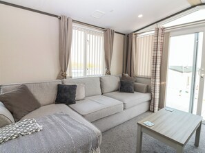 Ein modernes Wohnzimmer mit einer Couch, einem Couchtisch und Blick aus dem Fenster.