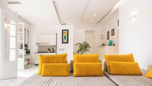 Una sala de estar moderna con un conjunto de sofás, un comedor y una cocina al fondo.