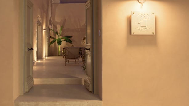A hallway leading to a dining area with a plant, a table, and chairs. - Moshoviti Residence (Rethymno)