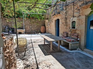 An outdoor seating area with a table and chairs, a stone wall, and a blue door. - Opuntia Stone House in Gavalochori village. (Gavalochori)