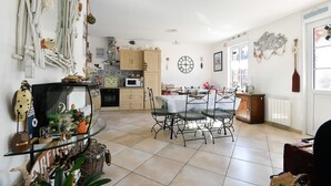 A spacious kitchen with a dining area, a glass-top table, and a variety of decorative items. - Apartment "Gîte Etienne Marie" with Private Terrace (Le Crotoy)