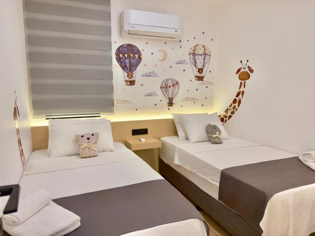 Ein Hotelzimmer mit zwei Betten, einem Nachttisch, einem Teddybären und einer Giraffendeko.