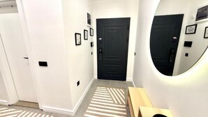 A hallway with a black door, a mirror, and a wooden bench. - SUNSET SUİTE 2+1 Family Apartment - 200m Walking Distance to the Beach (Kemer)