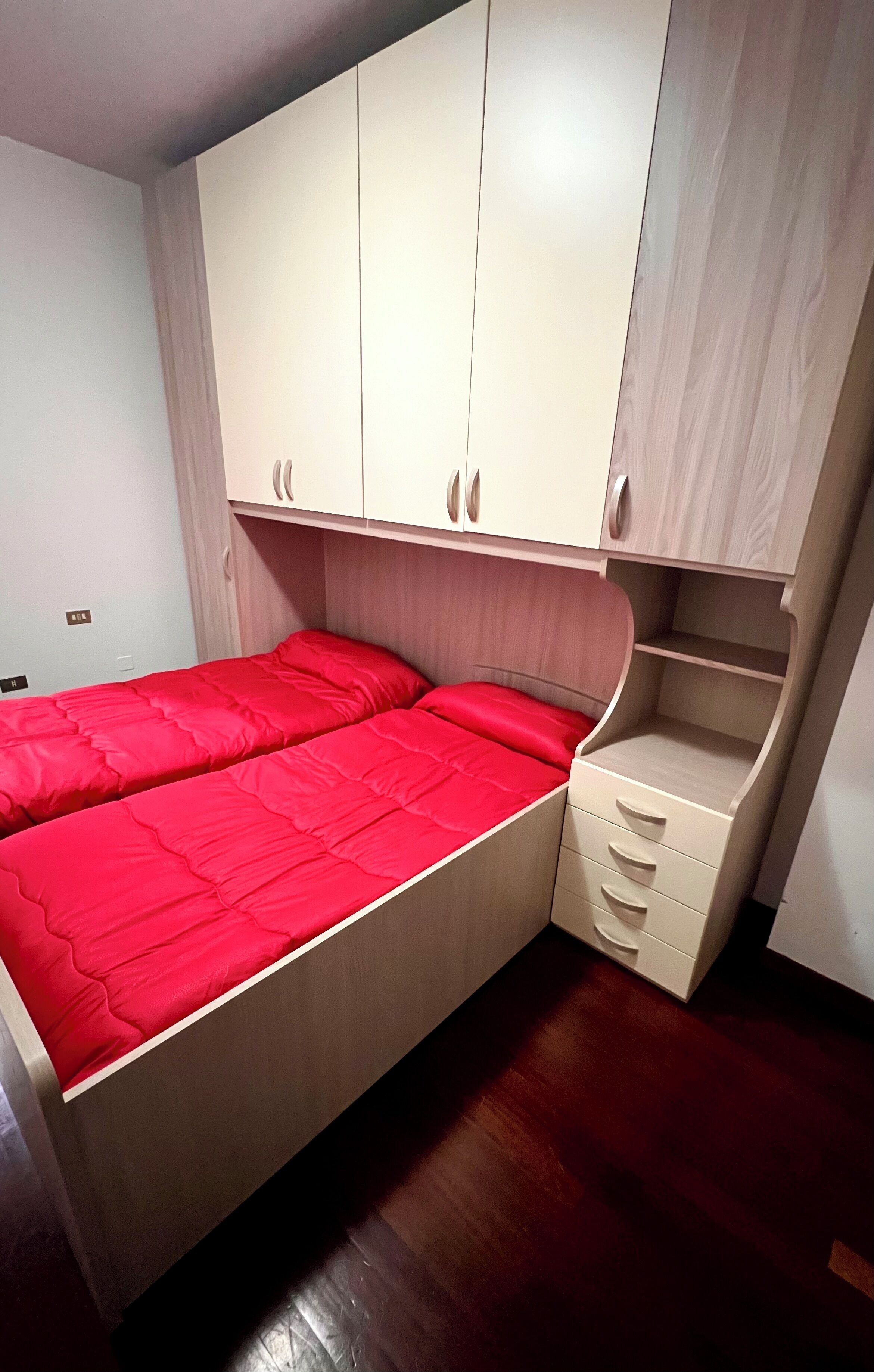 A bedroom with a bed, built-in wardrobe, and a small desk area.