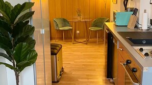 A compact kitchen with wooden flooring, a small dining area with two chairs, a coffee maker, and a toaster. - Cozy Home in Nature Park (Schlangenbad)
