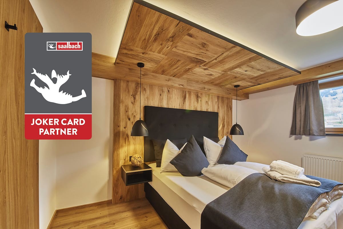 A wooden-paneled bedroom with a bed, bedside lamps, and a nightstand.