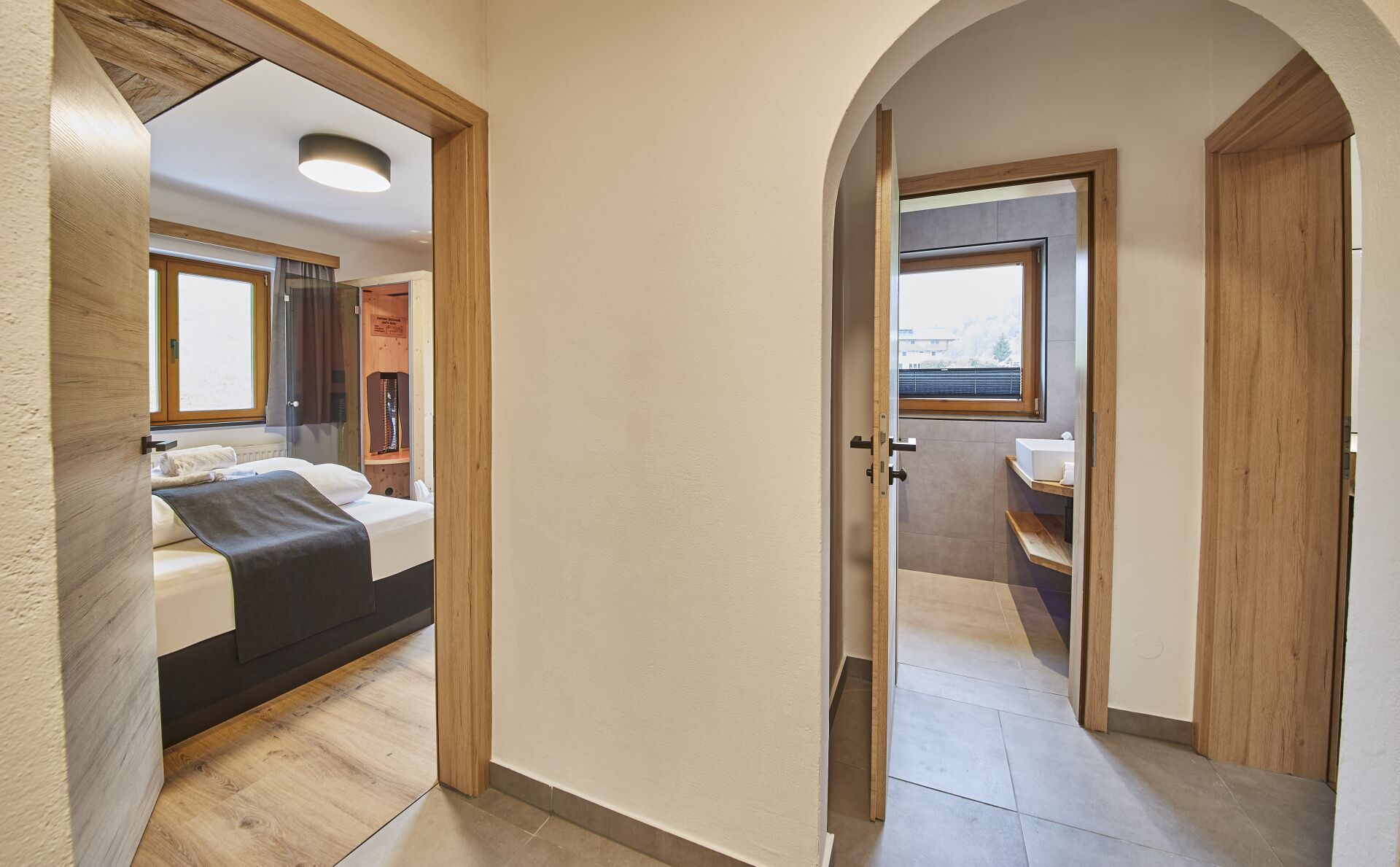 Ein Hotelzimmer mit Bett, Fenster und einem durch einen Bogen sichtbaren Badezimmer.