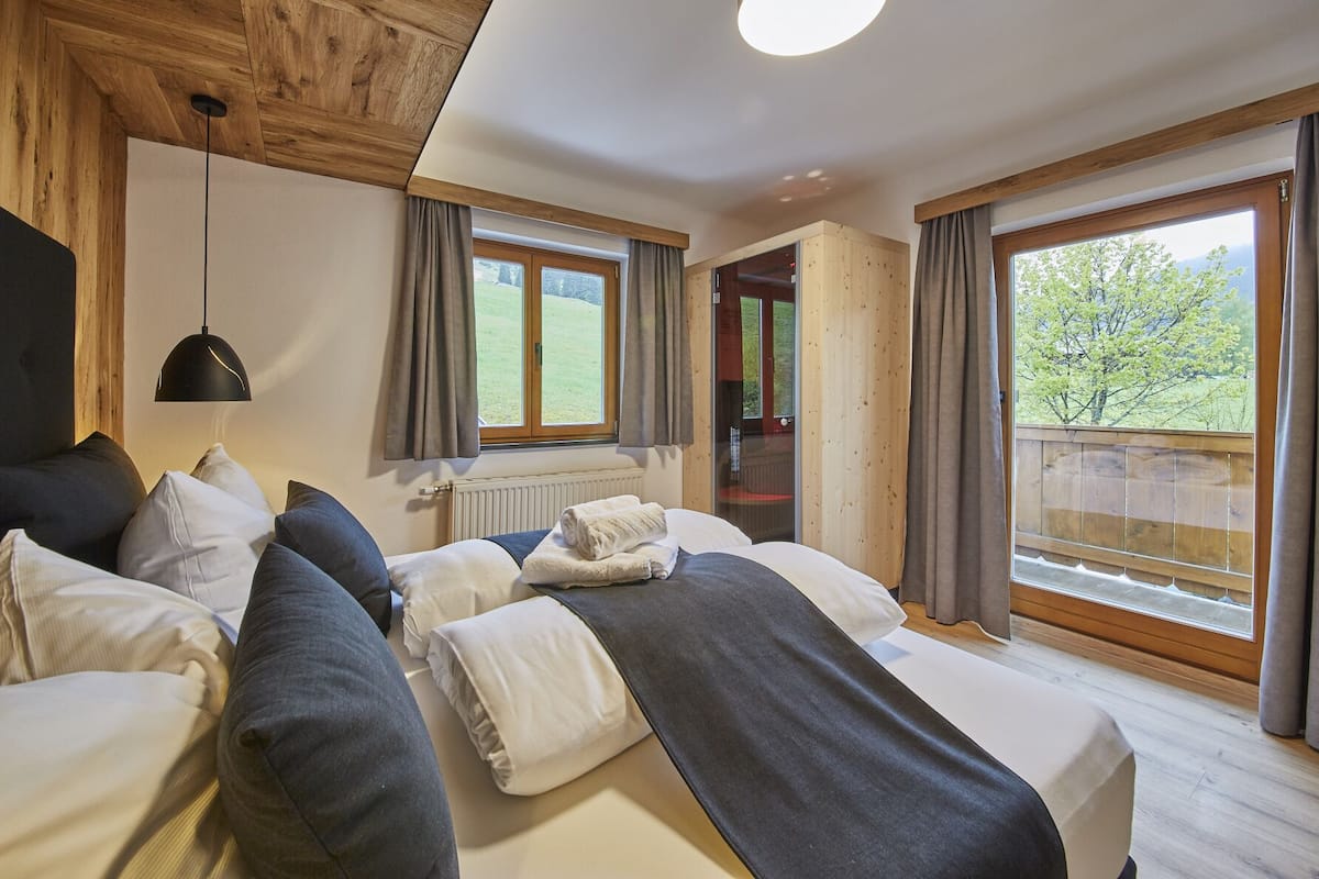 A bedroom with a bed, a hanging light, a window, and a view of the outdoors.