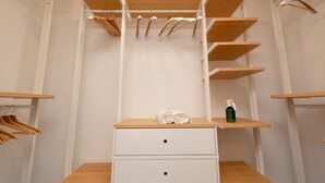 Ein begehbarer Kleiderschrank mit Holzböden, einer Kleiderstange und zwei Schubladen.