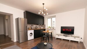 Eine moderne Küche mit einem Edelstahl-Kühlschrank, einer Waschmaschine und einem Essbereich mit Tisch und Stühlen.