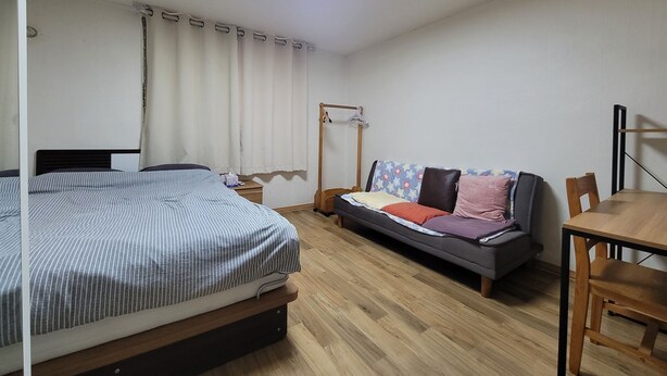 Une chambre avec un lit, un canapé, une table et un portant à vêtements.