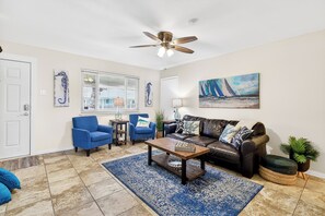 A living room with a ceiling fan, a coffee table, a sofa, two armchairs, a painting, and a window with blinds. - 2 Blocks to the Beach, Heated Pool, Sleep Number Mattress (Port Aransas)
