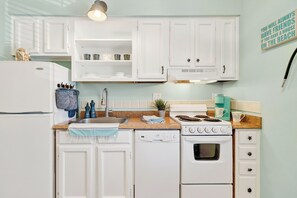 A kitchen with white cabinets, a dishwasher, an oven, a sink, and a countertop with various items. - 2 Blocks to the Beach, Heated Pool, Sleep Number Mattress (Port Aransas)