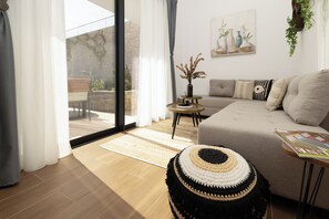 A living room with a sofa, a coffee table, a rug, and a window with curtains.