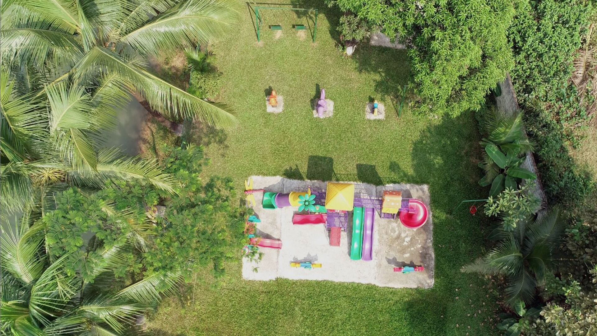 Une vue aérienne d’une aire de jeux avec des balançoires, des toboggans et un bac à sable.