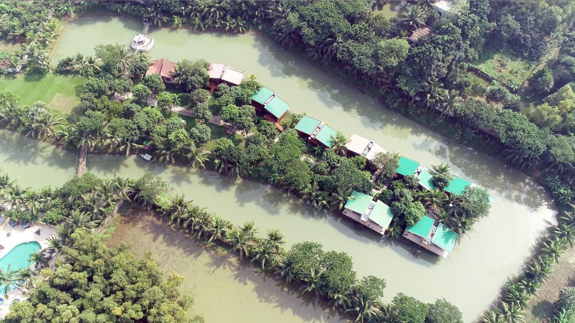 Vista aerea di un resort con diversi edifici, una piscina e una distesa d'acqua.