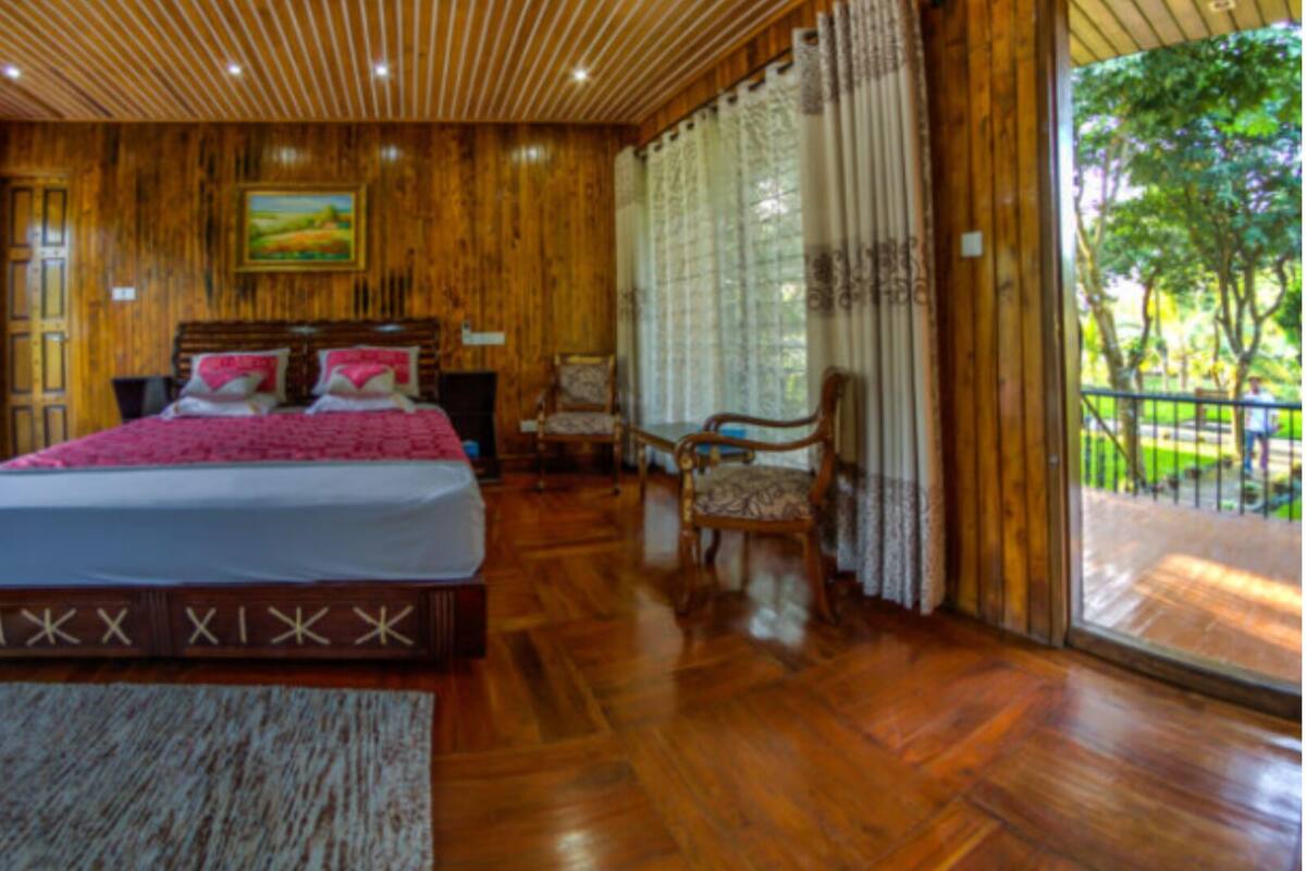 Un interior de madera con una cama, sillas y vistas por la ventana.
