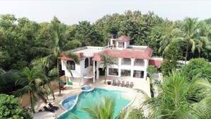 A two-story house with a swimming pool, surrounded by lush greenery. - Pubail Resort Club (Gazipur)