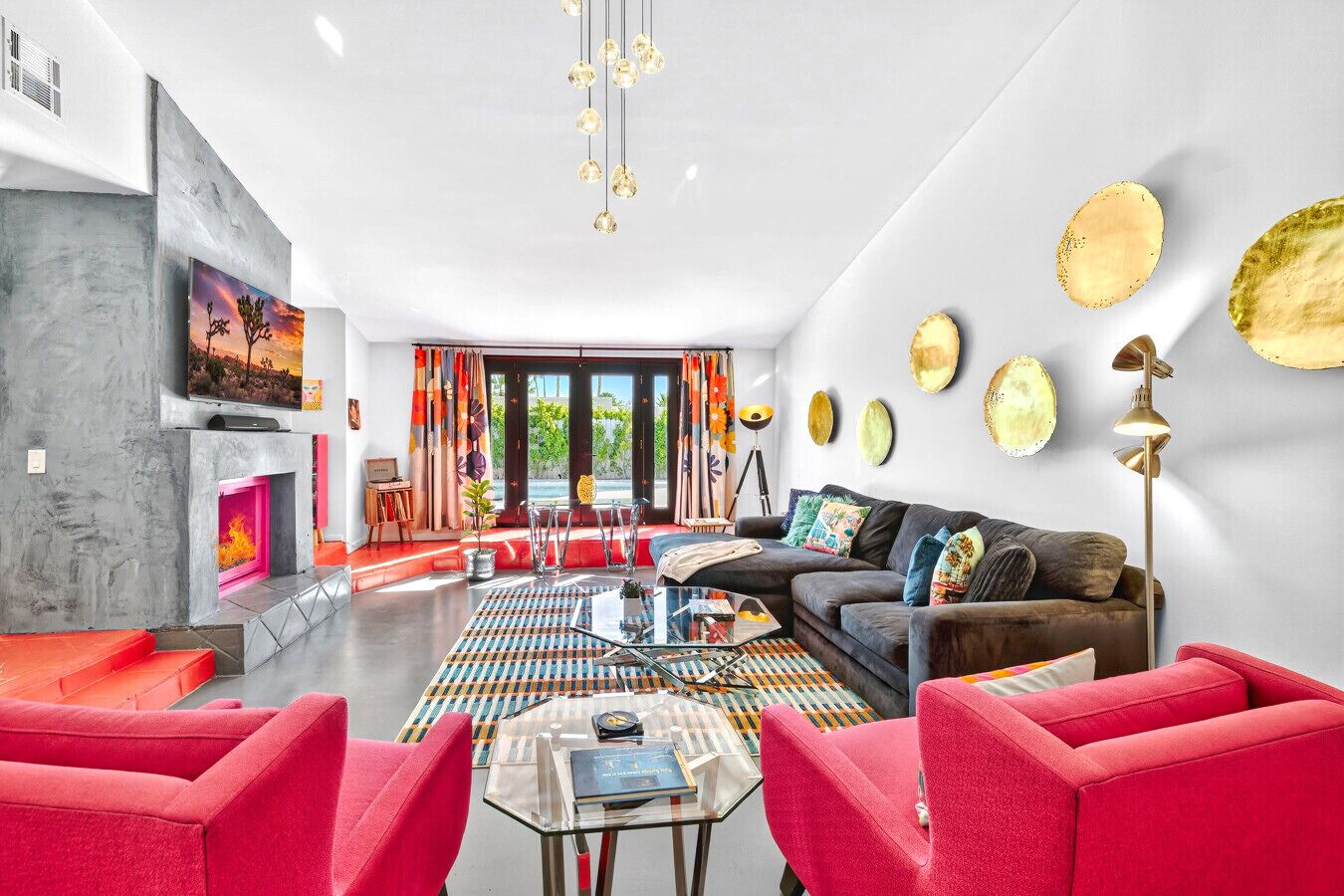A modern living room with a fireplace, red sofas, a coffee table, and a large TV.