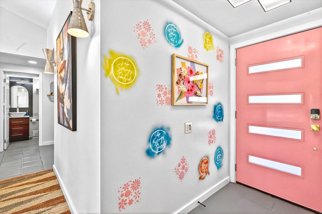 A hallway with a pink door, a framed picture, and decorative wall stickers.