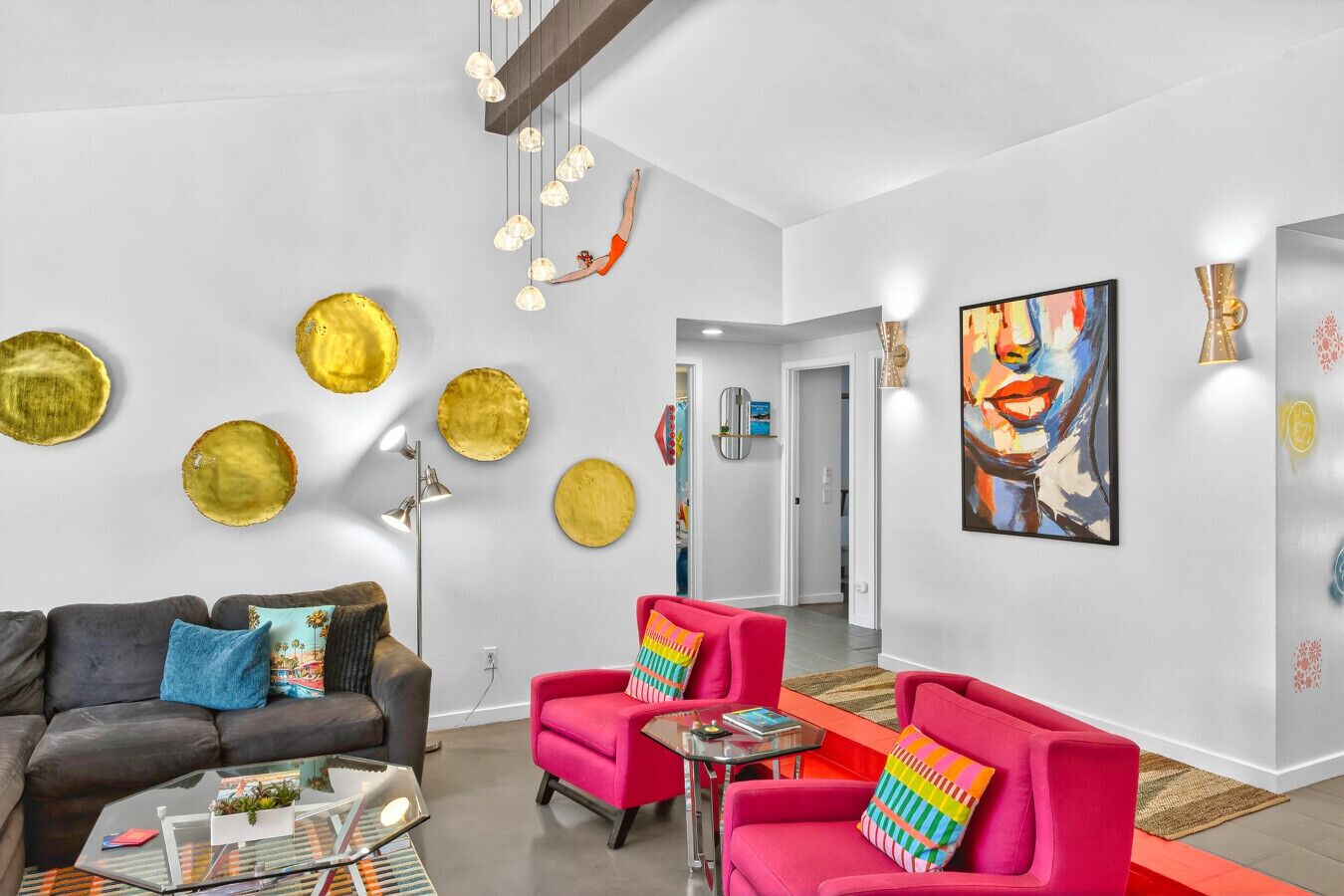 Un salon moderne avec un canapé gris, un fauteuil rouge et une table basse en verre.