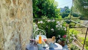 A stone wall, a round table with a tablecloth, a chair, and a basket of bread. - Charming bed and breakfast in an authentic Ardèche farmhouse. (Saint-Paul-le-Jeune)