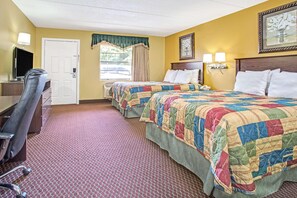 Ett hotellrum med två sängar, ett skrivbord, en stol och en tv.