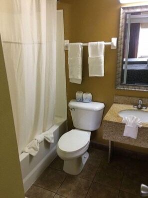 A bathroom with a toilet, a sink, and a shower curtain. - Days Inn by Wyndham Orange City/deland (Orange City)