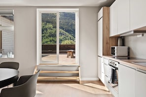 Una cocina moderna con un ventanal grande, banco de madera y electrodomésticos integrados.