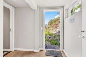 Un interior moderno con una puerta que da a un área exterior, un letrero que indica 'oddia Apartments' y vistas de una ladera.