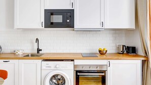Une cuisine moderne avec des meubles blancs, un four à micro-ondes en acier inoxydable, un lave-linge et un four.