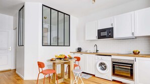 Une cuisine moderne avec des meubles blancs, un four à micro-ondes, un lave-linge et un four encastré.