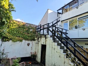 Una escalera que lleva a un edificio de fachada blanca y una pared cubierta de hiedra.