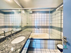 A bathroom with a glass-enclosed shower, a sink with a granite countertop, and a toilet. - Iate Plaza By Holiday Stays (Fortaleza)