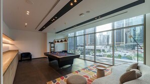 Ein modernes Wohnzimmer mit Billardtisch, einer Couch und einem großen Fenster mit Blick auf die Stadt.