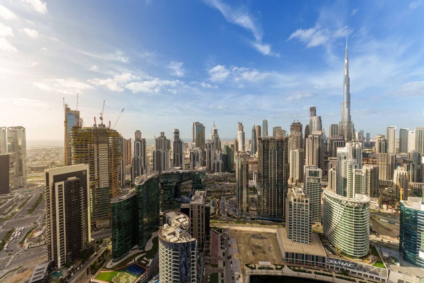 A cityscape with high-rise buildings, including a prominent skyscraper, and a large, curved building with a dome.