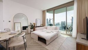 Ein modernes Hotelzimmer mit großem Bett, Essbereich, Sitzgelegenheit und einem Balkon mit Blick auf die Stadt.