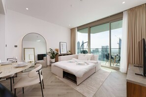 A modern hotel room with a large bed, a dining area, a sitting area, and a balcony with a city view. - Stunning 1 Bedroom Burj Khalifa View (Dubai)