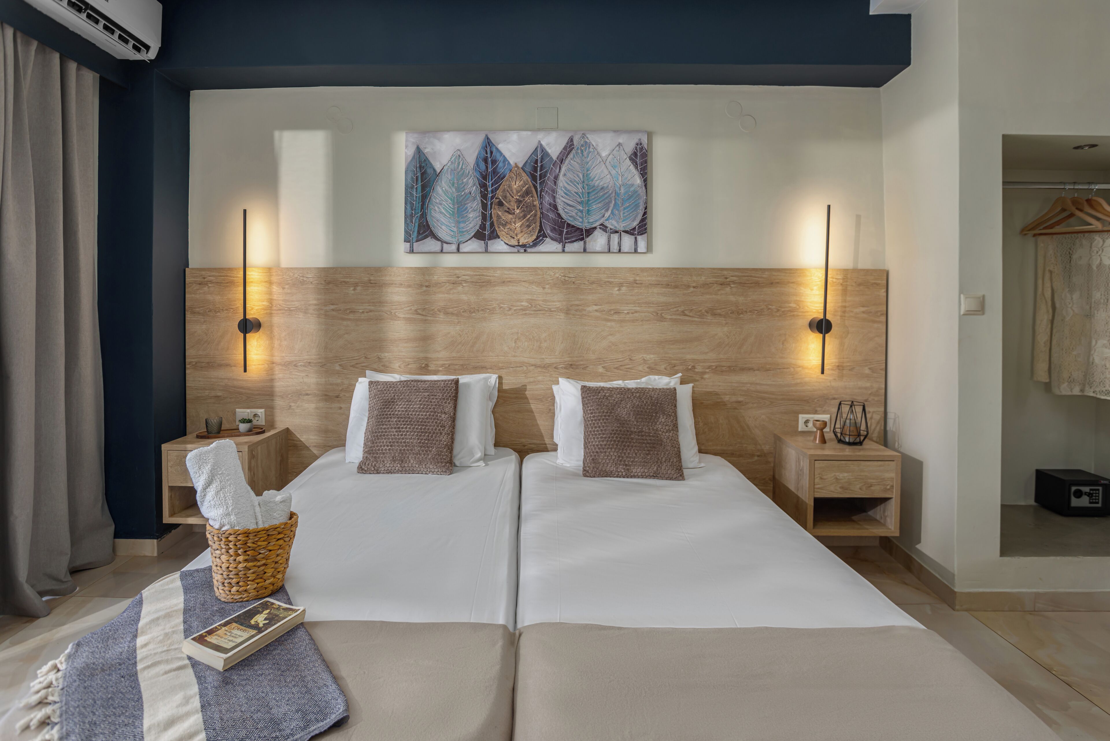 A double bed with a wooden headboard, two bedside tables with lamps, a wall-mounted artwork, and a hanging garment rack.