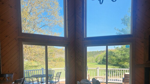 Un interior de madera con ventanas amplias, un sofá, una mesa de comedor y una araña.