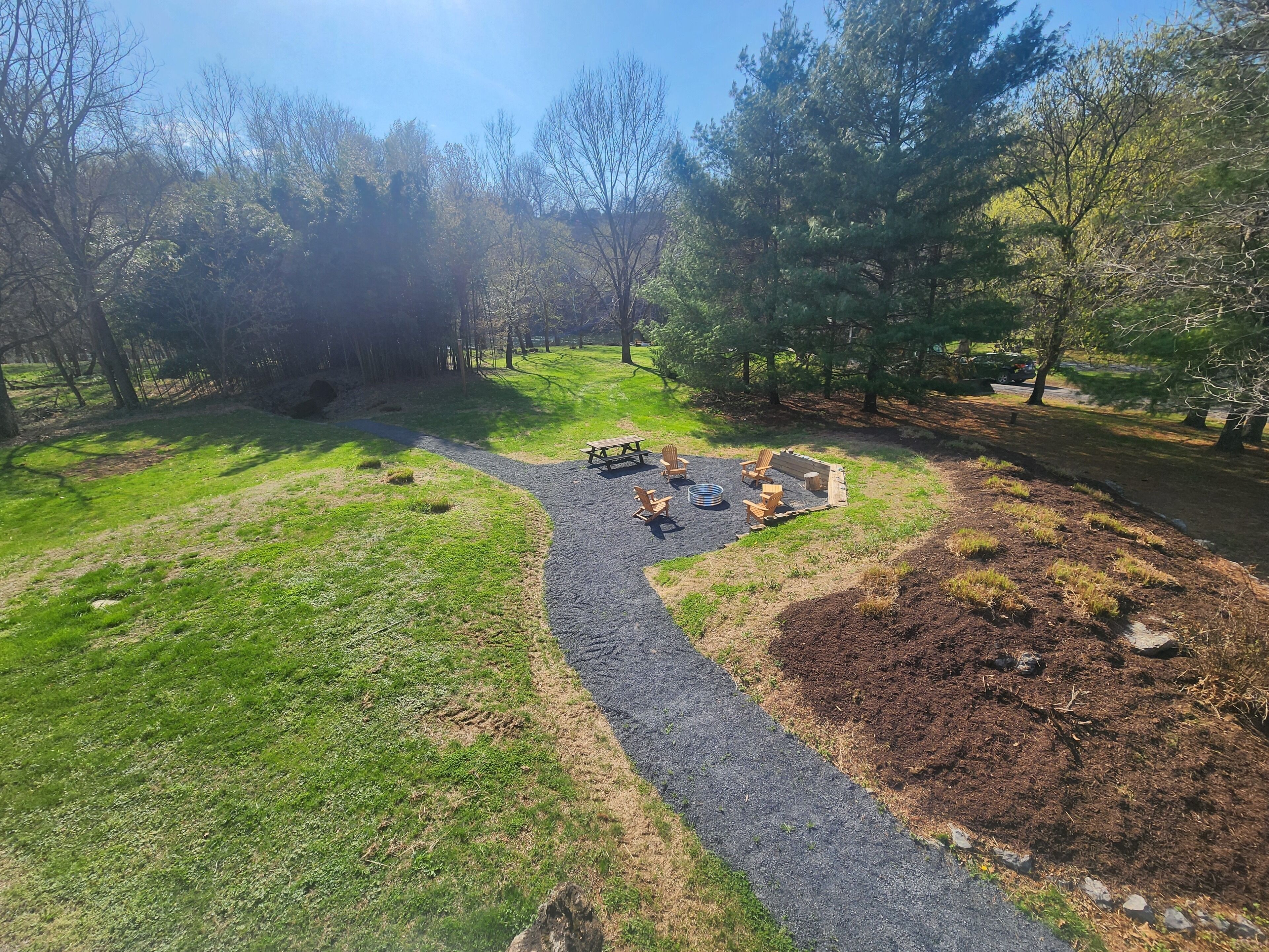 Ein Park mit Kiesweg, Picknicktischen und Sitzgelegenheiten.