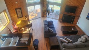 Un acogedor loft con techo de madera, un sofá, una mesa de comedor y un televisor.